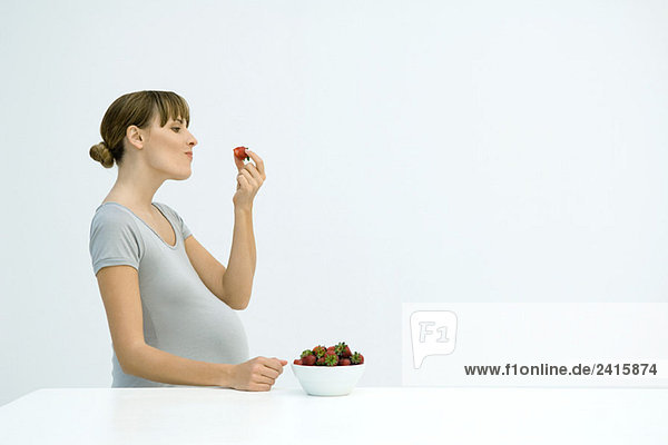 Schwangere Frau isst Erdbeeren aus einer Schale  Seitenansicht