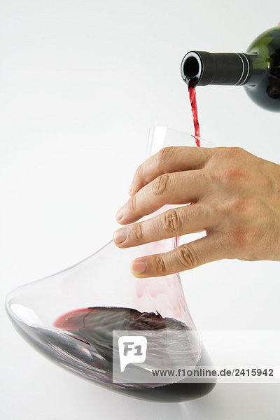 Mann gießt Rotwein in die Karaffe  Blick von Hand abgeschnitten