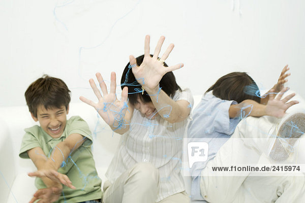 Mutter und zwei Söhne werden mit Sprühschnur besprüht  die Hände erhoben  lachend