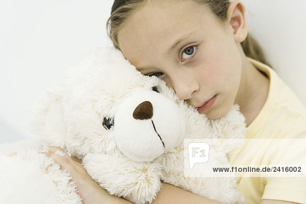 Kleines Mädchen umarmt Teddybär  schaut in die Kamera  Porträt