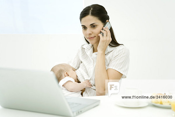 Frau Stillen Baby  mit Handy und Blick auf Laptop