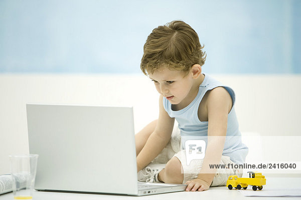 Kleiner Junge schaut auf Laptop-Computer