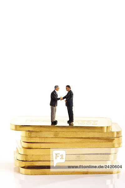 Geschäftsmännerfiguren auf einem Stapel Goldbarren stehend