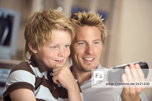 Vater und Sohn (10-11) schauen gemeinsam aufs Handy