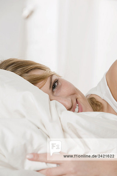 Blonde Frau entspannt im Bett  lächelnd  Portrait