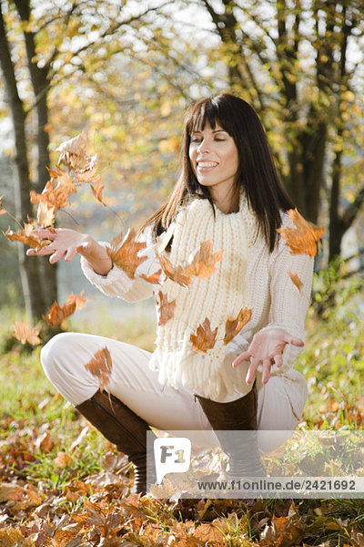 Brünette Frau spielt mit Herbstblättern