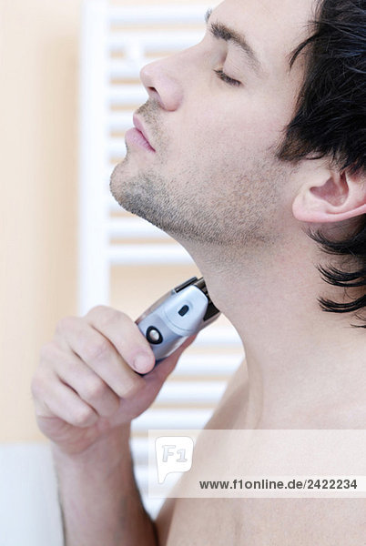 Young man using electric razor  portrait