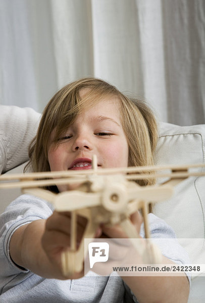Junge (8-9) hält Spielzeugflugzeug  Portrait