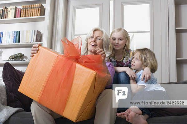 Grandmother and grandchildren (8-9) with gift