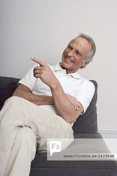 Senior man on sofa  smiling  portrait
