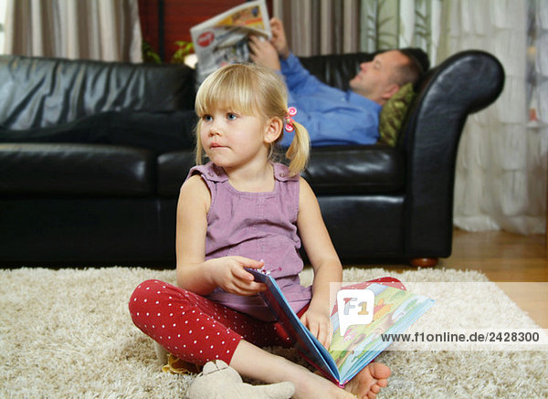 Girl sitting on carpet holding book