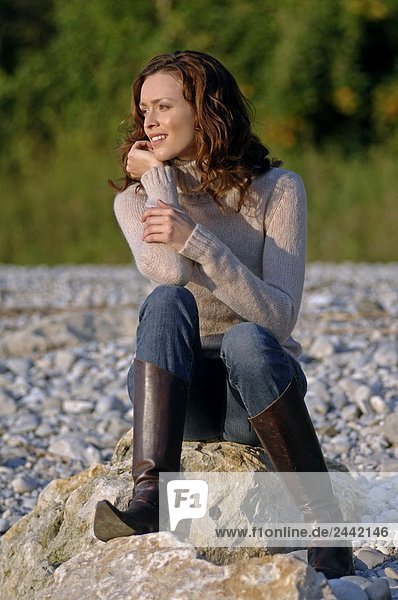 Frau sitzen auf Rock und lächelnd
