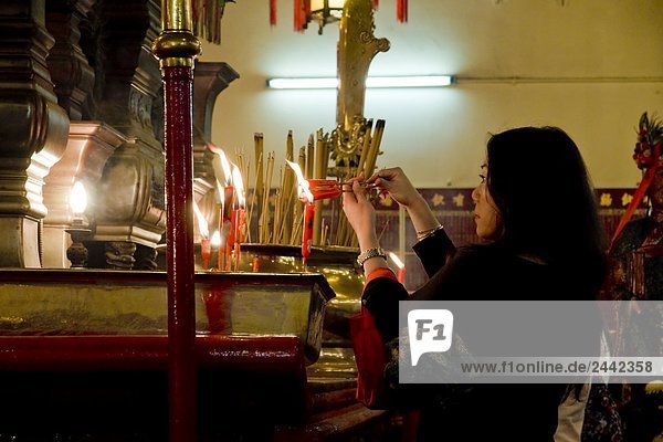 Woman lighting candle in Buddhist temple