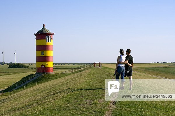 Rückansicht des zwei Personen stehen in der Nähe von Leuchtturm in Feld Pilsumer  Niedersachsen  Deutschland