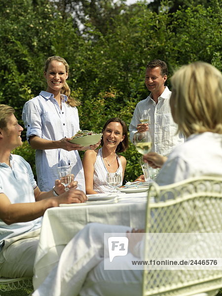 Fünf Menschen auf einer Gartenparty feiern