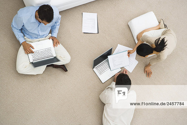 Geschäftsfreunde sitzen zusammen auf dem Boden  benutzen Laptops  Blick über den Kopf