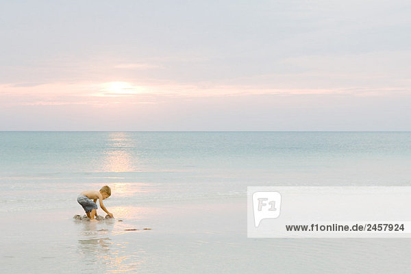 Kleiner Junge spielt am Strand bei Sonnenuntergang  Seitenansicht  volle Länge