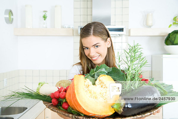 Frau hält Tablett mit frischem Gemüse  lächelt in die Kamera