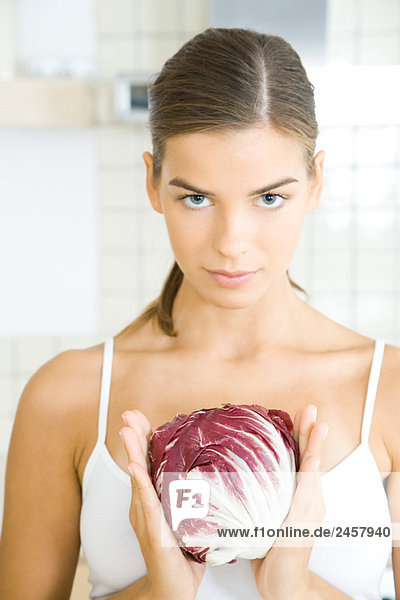 Young woman holding head of chicory  looking at camera