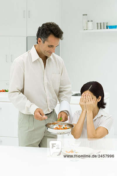 Ehemann serviert Frau Überraschungsmahlzeit  Frau bedeckt Augen mit Händen