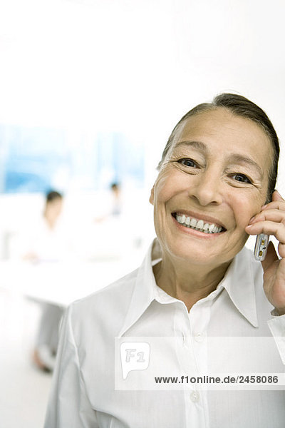 Senior woman using cell phone  smiling at camera
