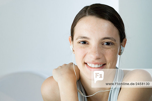 Junge Frau hört Kopfhörer  lächelt in die Kamera