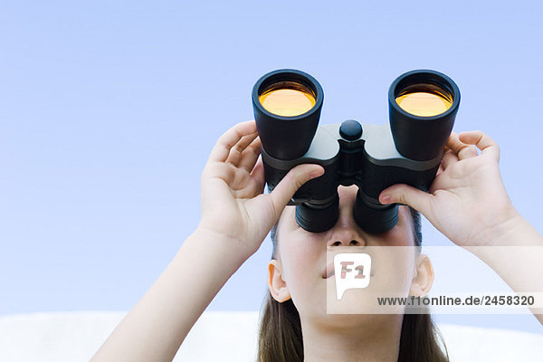 Preteen girl looking up through binoculars