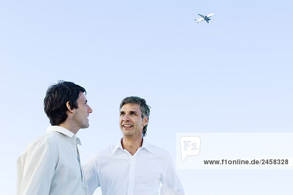 Zwei Männer  die miteinander reden  Flugzeug hoch im Hintergrund