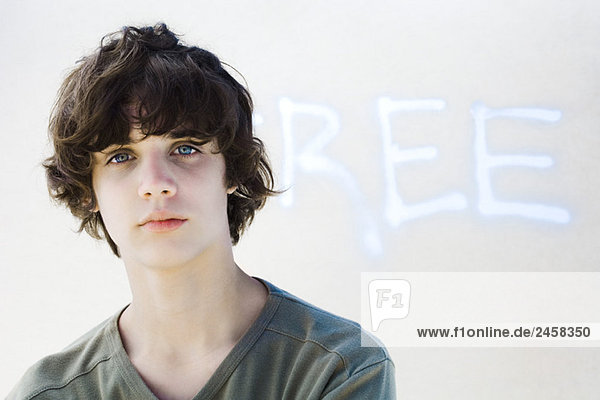 Teenager-Junge schaut in die Kamera  vor Graffiti