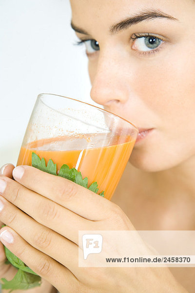Junge Frau trinkt ein Glas frischen Gemüsesaft.