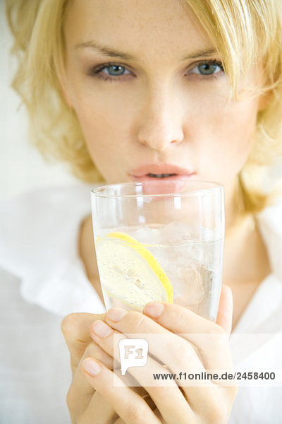 Junge Frau hält ein Glas Wasser hoch  Lippen  Kopf und Schultern  Mund