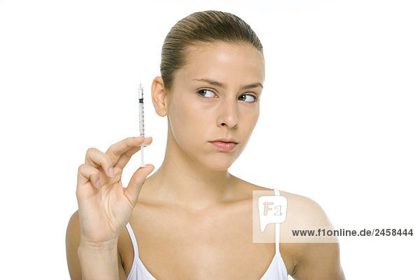 Young woman looking at syringe  close-up