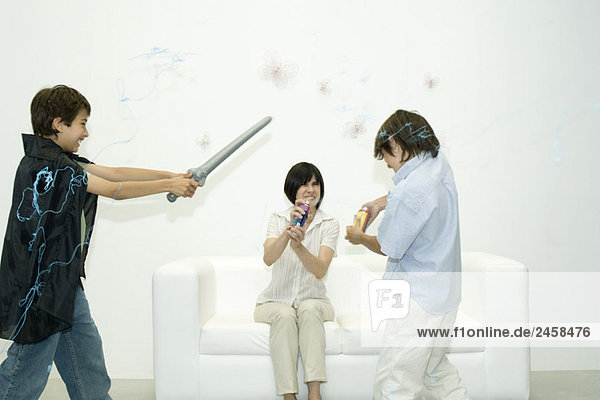Mutter und zwei Söhne spielen mit Sprayschnur  ein Junge hält das Schwert.