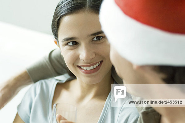 Junge Frau lächelt den Mann mit Weihnachtsmütze an  Nahaufnahme