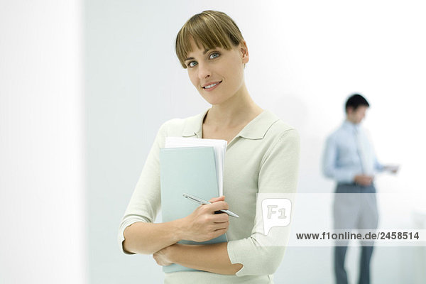 Female professional holding documents  smiling at camera