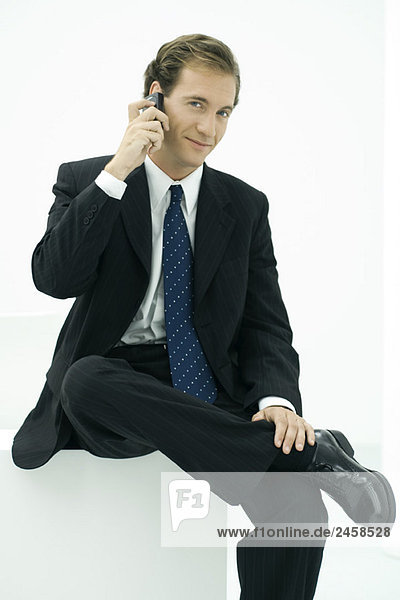 Businessman using cell phone  smiling at camera