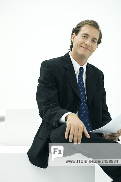 Businessman sitting  hand on knee  smiling at camera