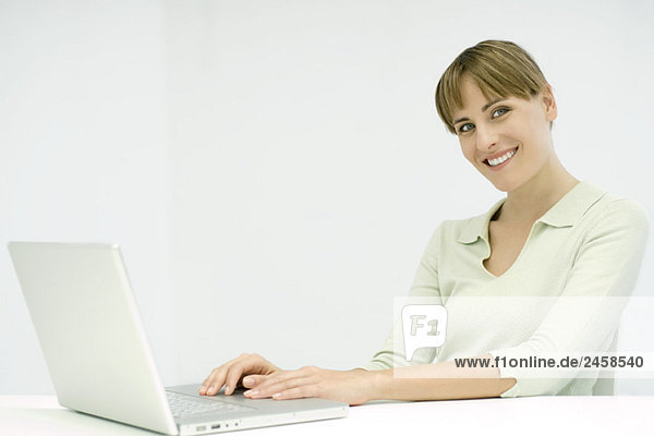 Woman using laptop computer  smiling at camera