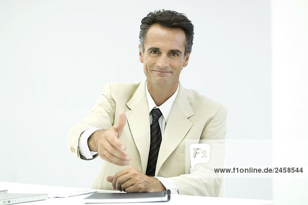 Businessman offering his hand to camera  smiling