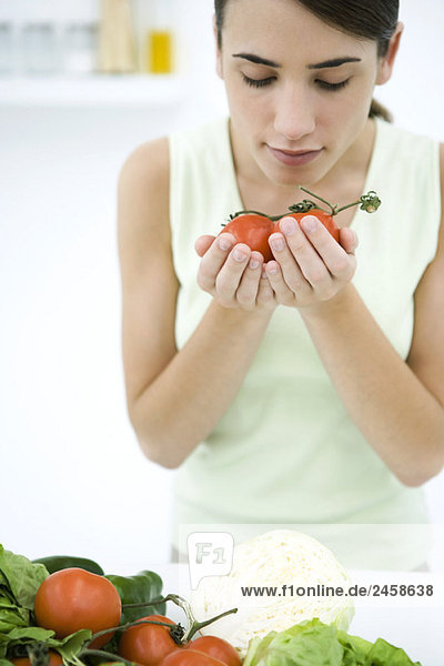Woman smelling ripe vine tomatoes  close-up