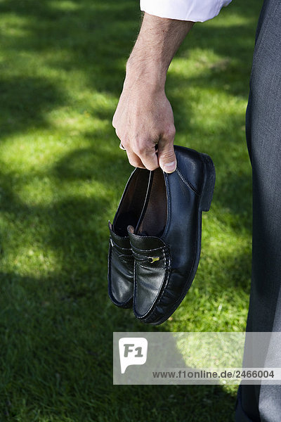 Kaufmann seine Schuhe in seine Hand Stockholm Schweden hält.