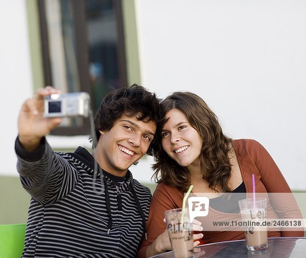 A young couple sitting at a caf holding a camera Portugal.