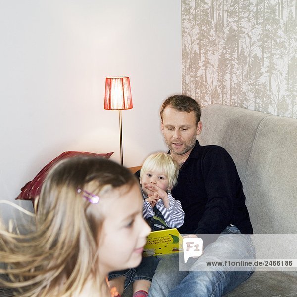 Father son and daughter reading a book together Sweden.