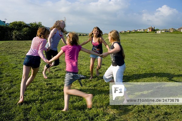 Children playing ring-a-ring-o-roses in field