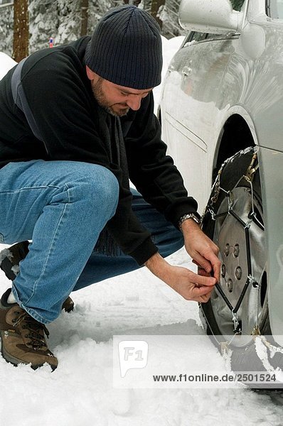 Man installing snow chains during winter