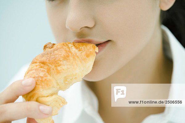 Junge Frau beim Croissantessen  Nahaufnahme  Ausschnittansicht
