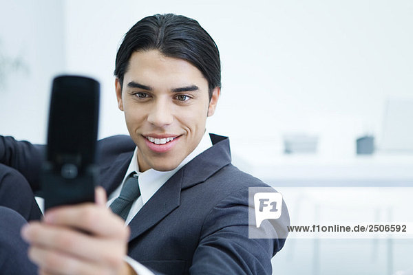 Junger Geschäftsmann mit dem Handy  um sich selbst zu fotografieren  lächelnd