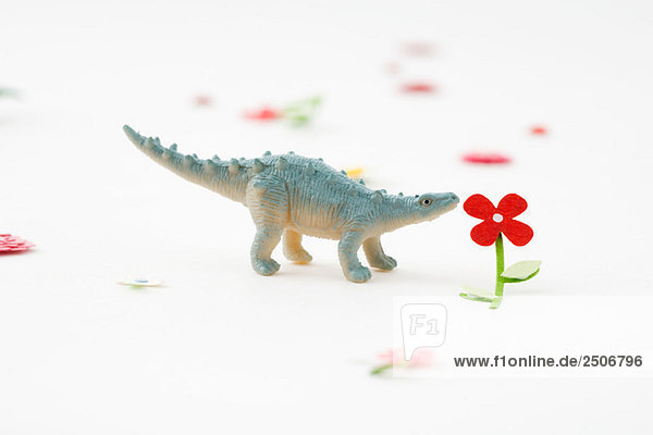 Spielzeug-Dinosaurier riechende Kunstblume