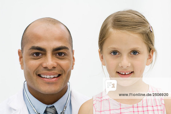 Male doctor beside girl  both smiling at camera  portrait