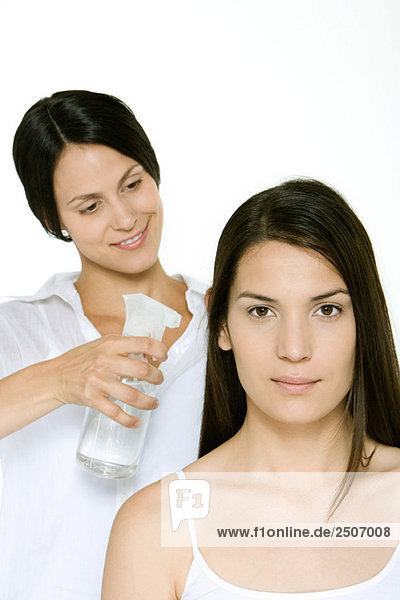 Friseurin mit Sprühflasche zum Befeuchten von Frauenhaaren